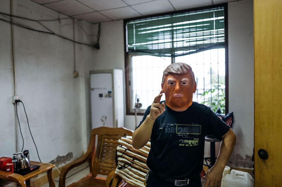 SHENZHEN, CHINA - OCTOBER 18: An employee wearing a mask of Donald Trump poses for a photograph at the Shenzhen Lanbingcai Latex Crafts Factory on October 18, 2016 in Shenzhen, China. Shenzhen Lanbingcai Latex Crafts Factory, located in the industrial area of Shenzhen with 20 to 30 employees, produces all sort of Halloween and party costumes and masks. It runs a small scale production of Donald Trump masks for local distribution within mainland China costing from 30 Renminbi onwards as the third Presidential Debate 2016 between Donald Trump and Hillary Clinton happens on Thursday. Chinese media have derided the election as a risible variety show in which the candidates' spectacular personal failings have taken precedence over the business of governance.