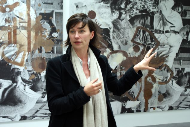 A curator stands in front of a work by Kelley Walker.