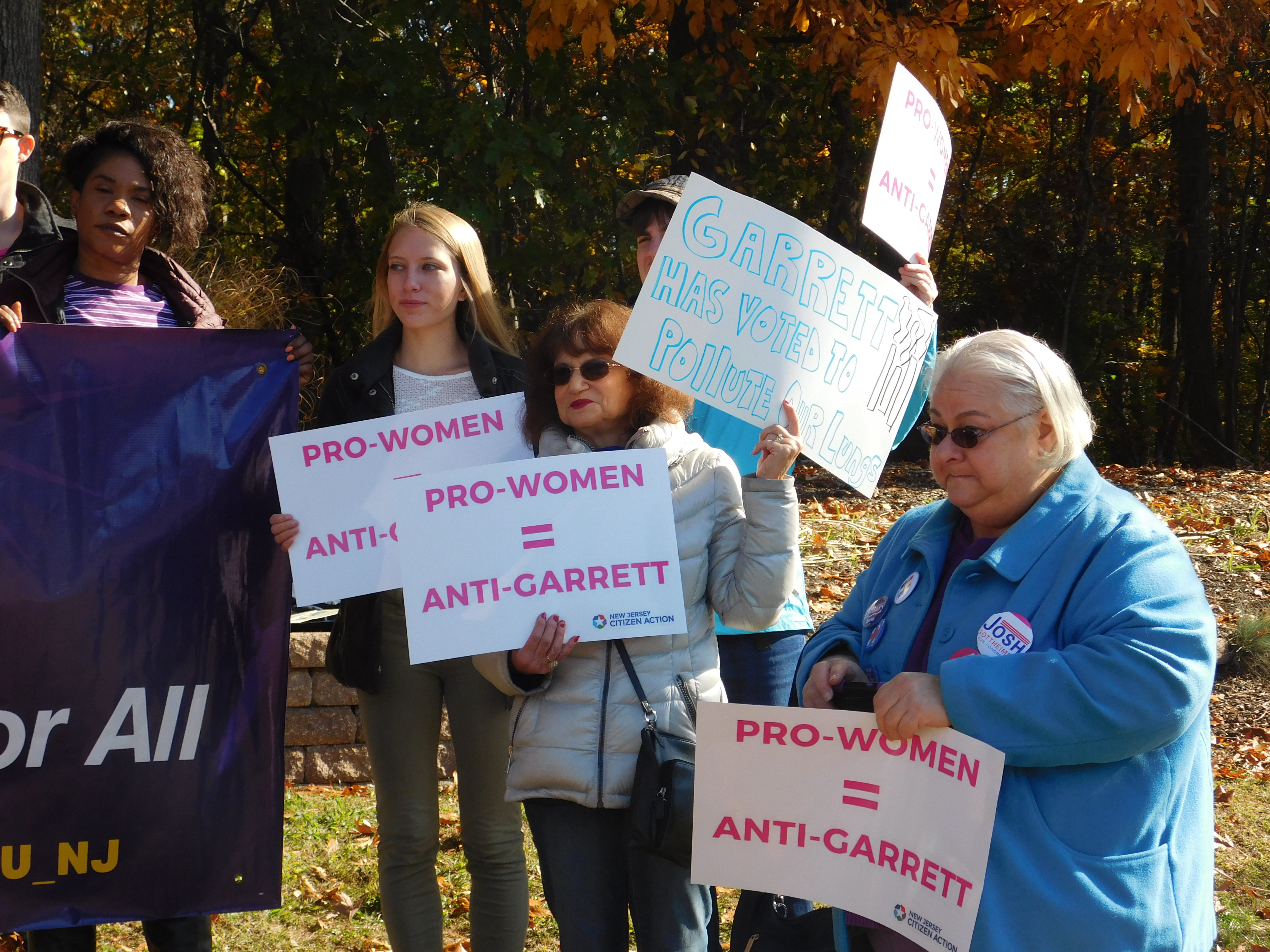 Attendees hold signs reading 'Pro-women = anti-Garrett."