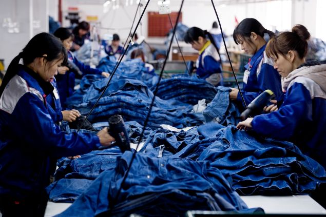 XINTANG, CHINA - Workers manufacture blue jeans in Congshin textile factory on February 9, 2012 in Xintang, Guangdong province, China.The town of Xintang, nicknamed "the denim jeans center of the world, claims to produce 60% of the world global output of jeans.