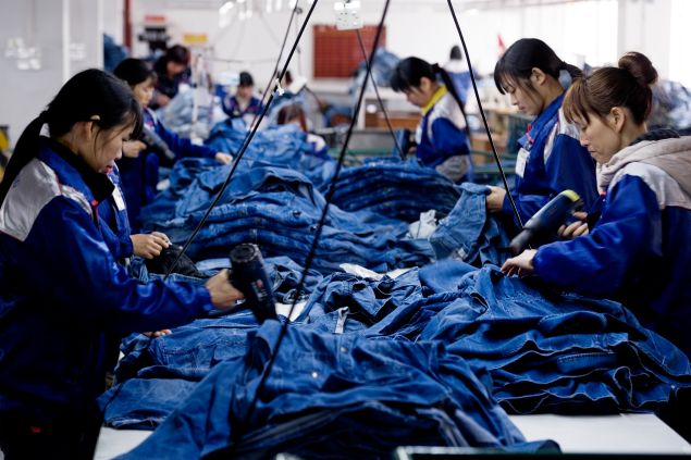 XINTANG, CHINA - Workers manufacture blue jeans in Congshin textile factory on February 9, 2012 in Xintang, Guangdong province, China.The town of Xintang, nicknamed "the denim jeans center of the world, claims to produce 60% of the world global output of jeans. 