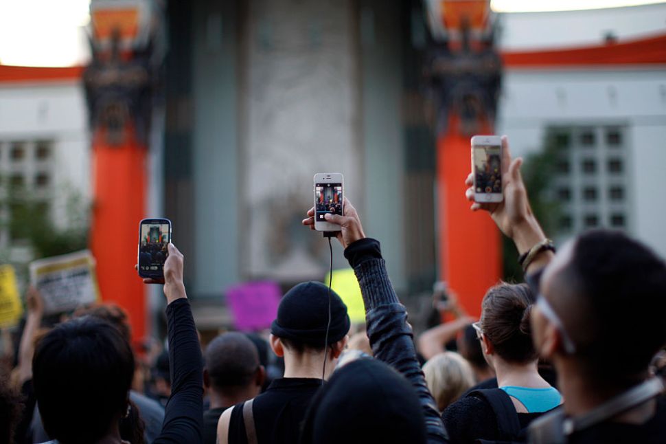 LOS ANGELES, CA - DECEMBER 6: People aim cell phones at a speaker in front of the TCL Chinese Theatre as they march on Hollywood Boulevard to protest of the decision in New York not to indict a police officer involved in the choke-hold death of Eric Garner on December 6, 2014 in the Hollywood section of Los Angeles, California. The march passed the tourist attraction of Hollywood and Highland where police had previously shot and killed a man that according to police had a knife. (Photo by David McNew/Getty Images)