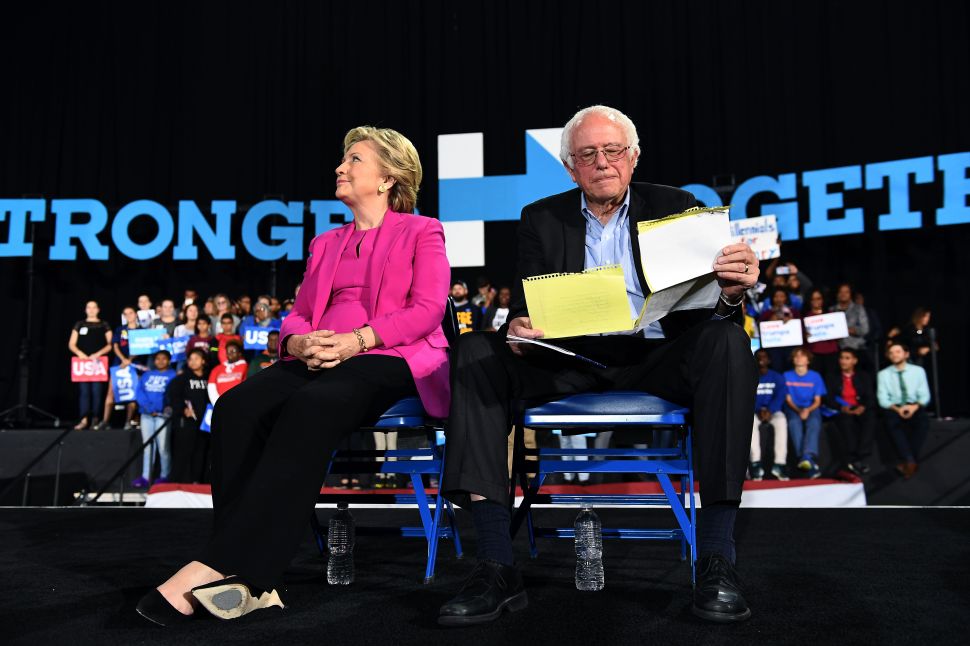 US Democratic presidential nominee Hillary Clinton and Bernie Sanders listen to singer Pharrell Williams during a campaign rally in Raleigh, North Carolina, on November 3, 2016.