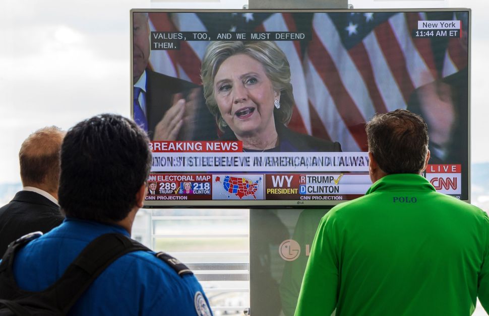 People walking at Ronald Reagan National Airport airport gather around a television monitor and watch US Democratic nominee Hillary Clinton deliver her concession speech November 9, 2016, a day following the election that US Republican nominee Donald Trump won in Arlington, Virginia. / AFP / PAUL J. RICHARDS        