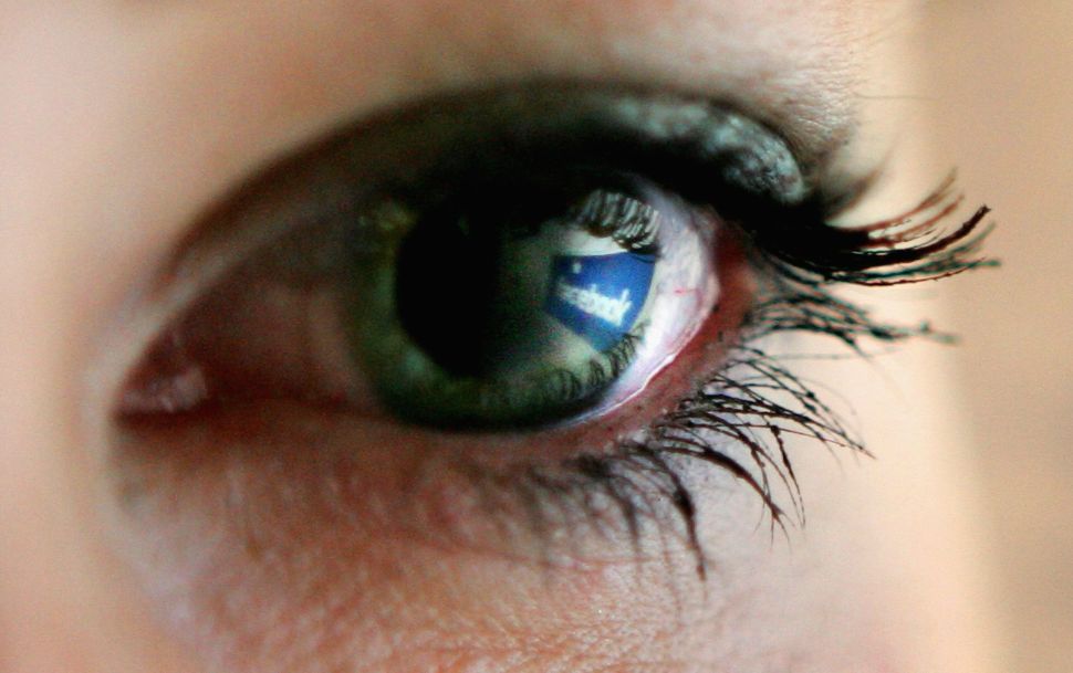 Facebook logo is reflected in an eye. 