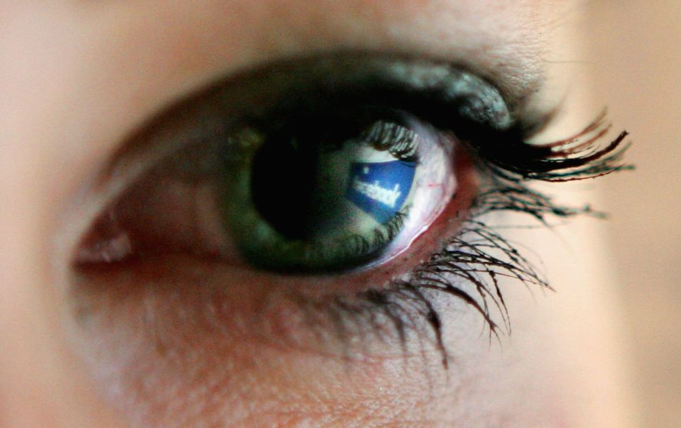 Facebook logo is reflected in an eye.