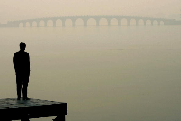 A man looks towards a bridge in heavy fog on December 14, 2004 in Beijing, China.