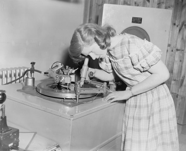 Student Jean Cooke using a microscope to examine the grooves of a record she has just cut, at Wood Norton, a stately home near Evesham, Worcestershire, which is home to the BBC Engineering Training Department, 24th May 1956.