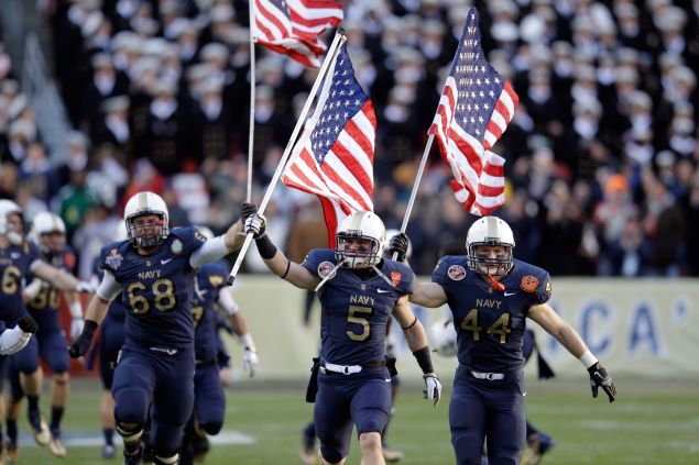 John Dowd #68, Brian Blick #5, and Max Blue #44 of the Navy Midshipmen carry the American flags onto the field before the start of the 112th annual Army-Navy Game of the Navy Midshipmen at FedEx Field on December 10, 2011 in Landover, Maryland.