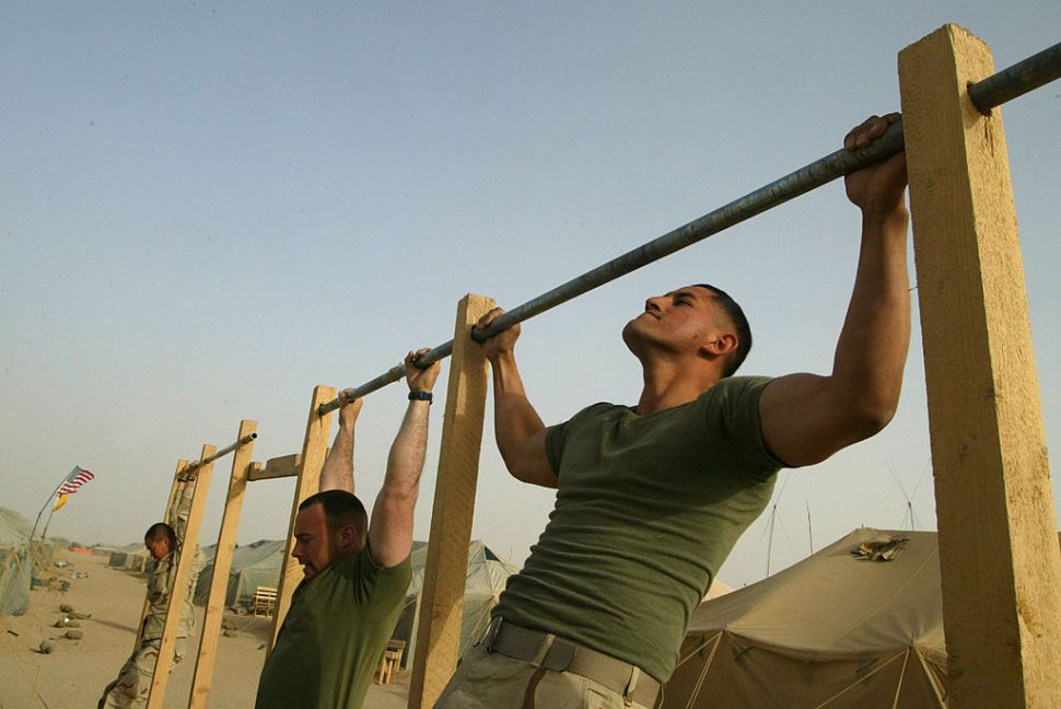 CAMP SHOUP, KUWAIT - MARCH 13: (L-R) U.S. Marines Corporal Norman Doran from Columbus, Ohio and Lance Corporal Diego Carrion from Miami, Florida of Task Force Tarawa do pull-ups March 13, 2003 near the Iraqi border in Kuwait. Thousands of U.S. Marines and soldiers are in the Kuwaiti desert waiting for any orders to attack Iraq.