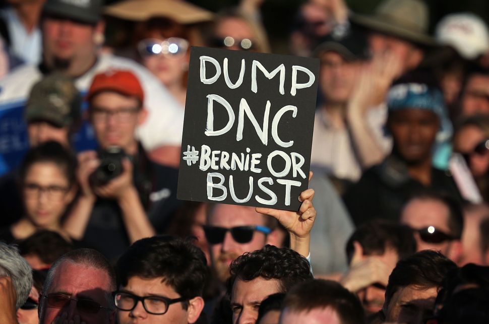 A supporter holds up a "DUMP DNC" sign during a rally of Democratic presidential candidate Sen. Bernie Sanders near the Robert F. Kennedy Memorial Stadium June 9, 2016 in Washington, DC.