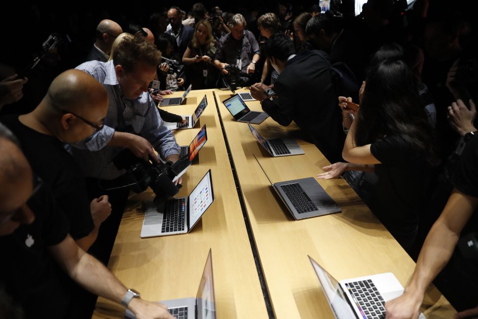 Members of the media gather around a table displaying the new Apple MacBook Pro laptop after the product launch event on October 27, 2016 in Cupertino, California.