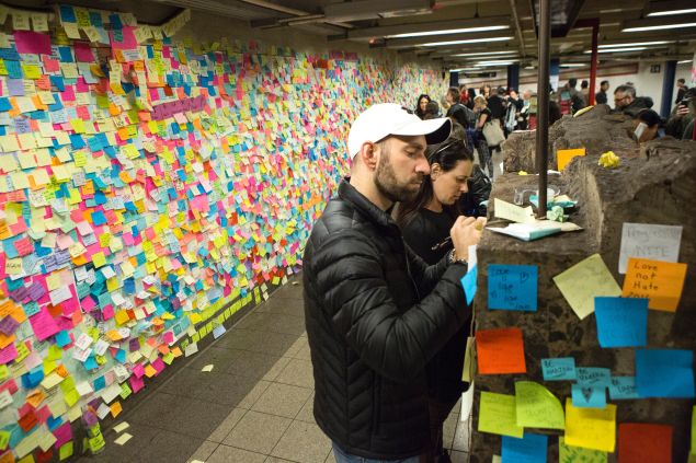 People stick a Post-It note to participate in the art piece 'Subway Therapy' at the Union Square subway station in New York on November 17, 2016 "Subway Therapy" allows people to express their thoughts with the public, and began after the November 8, 2016 US presidential election.