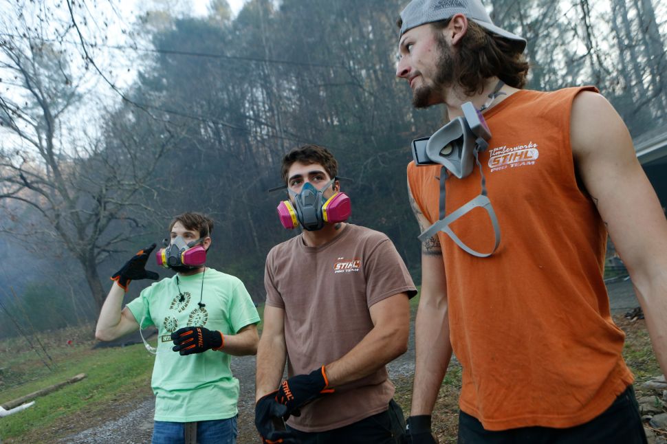 Residents Kirk Wallace, Caleb Graves and Tyler Alden gather to clear debris and put out small fires near surrounding homes as the remains of their neighbors' homes smolder after a wildfire November 29, 2016 in Gatlinburg, Tennessee.