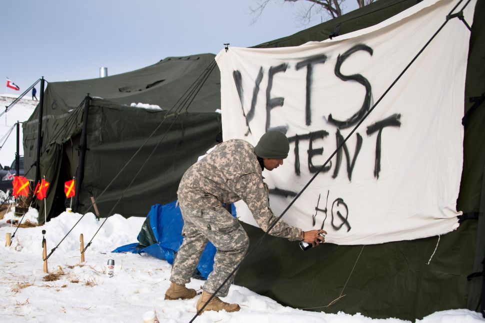 US Army veteran Zhooniya Ogitchida spray paints a sign for the veterans headquarters tent at the Oceti Sakowin Camp on the edge of the Standing Rock Sioux Reservation on December 3, 2016 outside Cannon Ball, North Dakota.