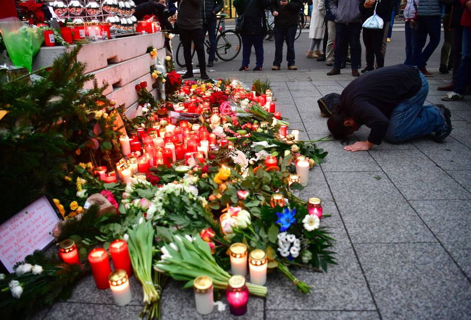 A Muslim mam prays at a makeshift memorial for the attack victims, on December 20, 2016 in front of the Kaiser-Wilhelm-Gedaechtniskirche (Kaiser Wilhelm Memorial Church) in Berlin, where a truck crashed into a Christmas market. Twelve people were killed and almost 50 wounded, 18 seriously, when the lorry tore through the crowd on December 19, 2016, smashing wooden stalls and crushing victims, in scenes reminiscent of July's deadly attack in the French Riviera city of Nice. / AFP / John MACDOUGALL