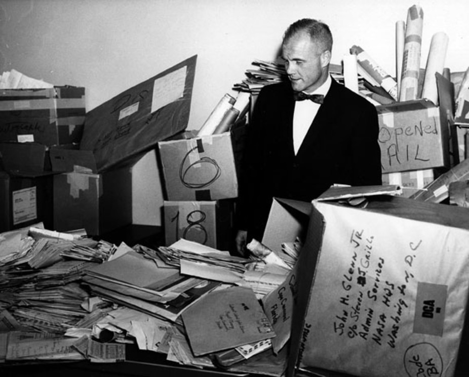 John Glenn stands in the NASA mail room surrounded by thousands of letters sent to him. 