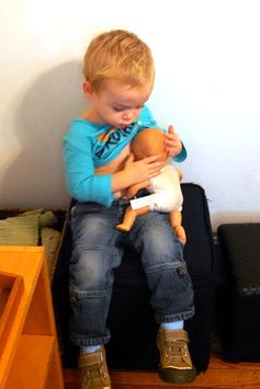 A boy nursing his doll.