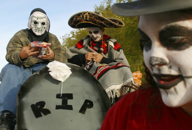 ALBUQUERQUE, NM - NOVEMBER 3: Ray Griego (L), 14, and Emiliano Martinez (C), 13, ride on a float in the 10th annual Day of The Dead Parade November 3, 2002 in Albuquerque, New Mexico. The parade is organized by the Raramuri Center, New Mexico Arts and the New Mexico Endowment For The Arts as a way to bring the community together. (Photo by Phillippe Diederich/Getty Images)