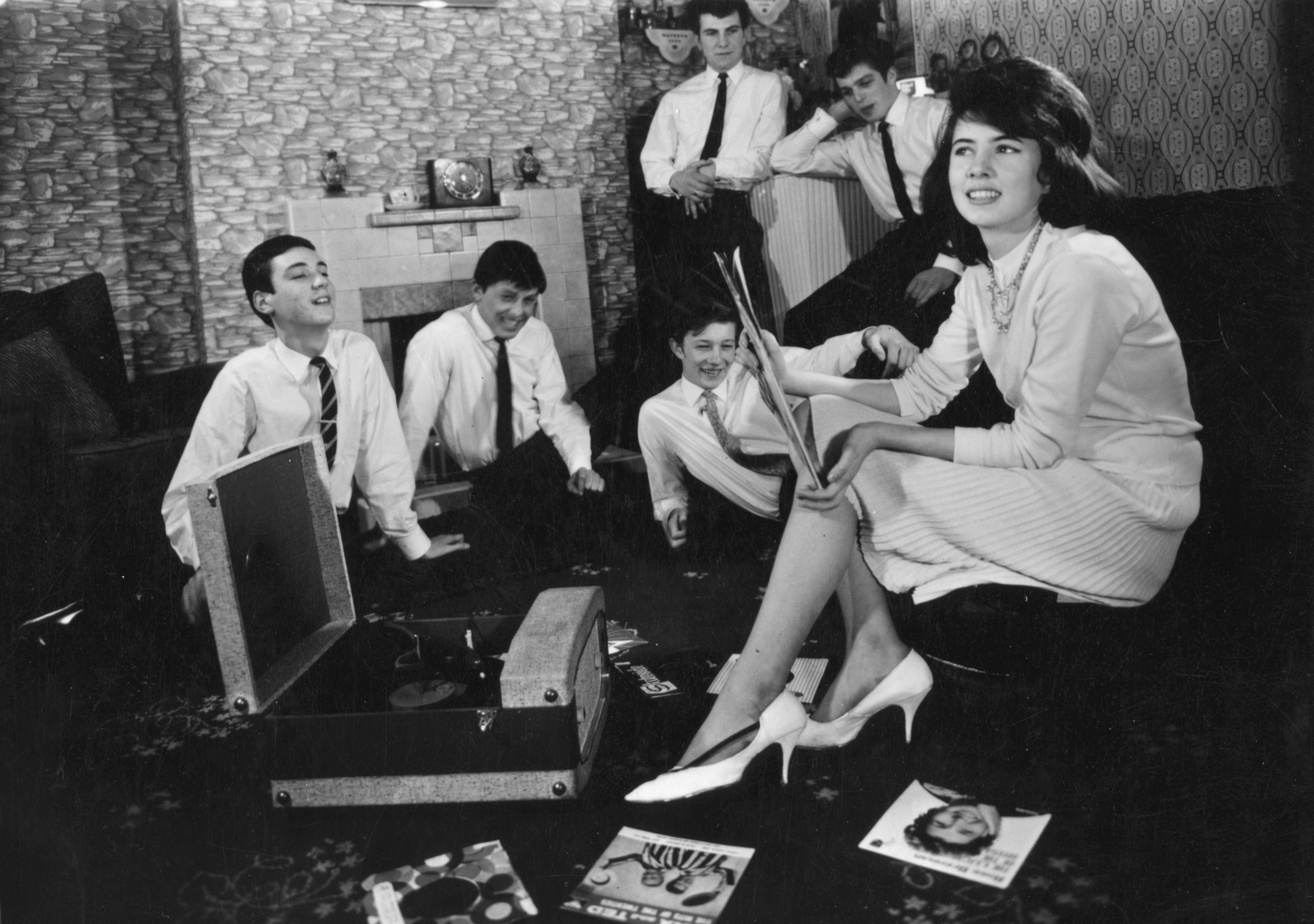 circa 1960: A group of teenagers listening to some records at home.