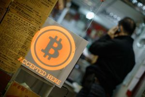 A man talks on a mobile phone in a shop displaying a bitcoin sign during the opening ceremony of the first bitcoin retail shop in Hong Kong on February 28, 2014. Bitcoin was invented in the wake of the global financial crisis by a mysterious computer guru using the pseudonym Satoshi Nakamoto and unlike other currencies, it does not have the backing of a central bank or government. AFP PHOTO / Philippe Lopez (Photo credit should read PHILIPPE LOPEZ/AFP/Getty Images)