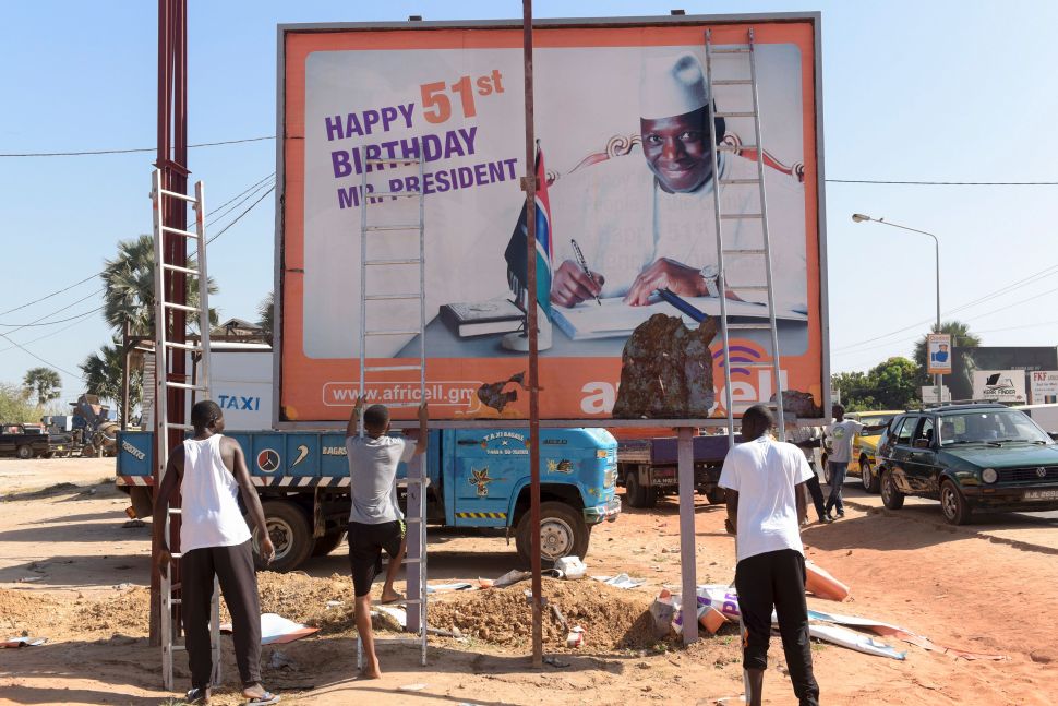 Workers prepare to remove an electoral poster of Gambia's outgoing president Yahya Jammeh.