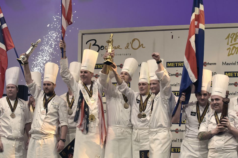 First place winner American Chef Mathew Peters (C), second place Norway's chef Christopher W. Davidsen (L) and third place Iceland's chef Viktor Andresson (R) hold their trophies as they celebrate on the podium after competing in the final event of the Bocuse d'Or International culinary competition, on January 25, 2017 during the catering and food international show (SIRHA), in the French central town of Chassieu, near Lyon. / AFP / JEAN-PHILIPPE KSIAZEK