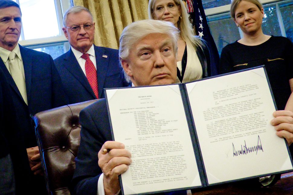 President Donald Trump holds up one of the executive actions that he signed in the Oval Office .