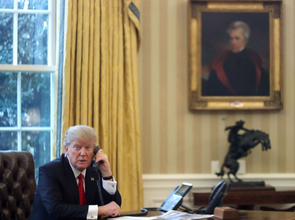 WASHINGTON, DC - JANUARY 29: President Donald Trump is seen through a window speaking on the phone with King of Saudi Arabia, Salman bin Abd al-Aziz Al Saud, in the Oval Office of the White House, January 29, 2017 in Washington, DC. On Sunday, President Trump is making several phone calls with world leaders from the Oval Office.