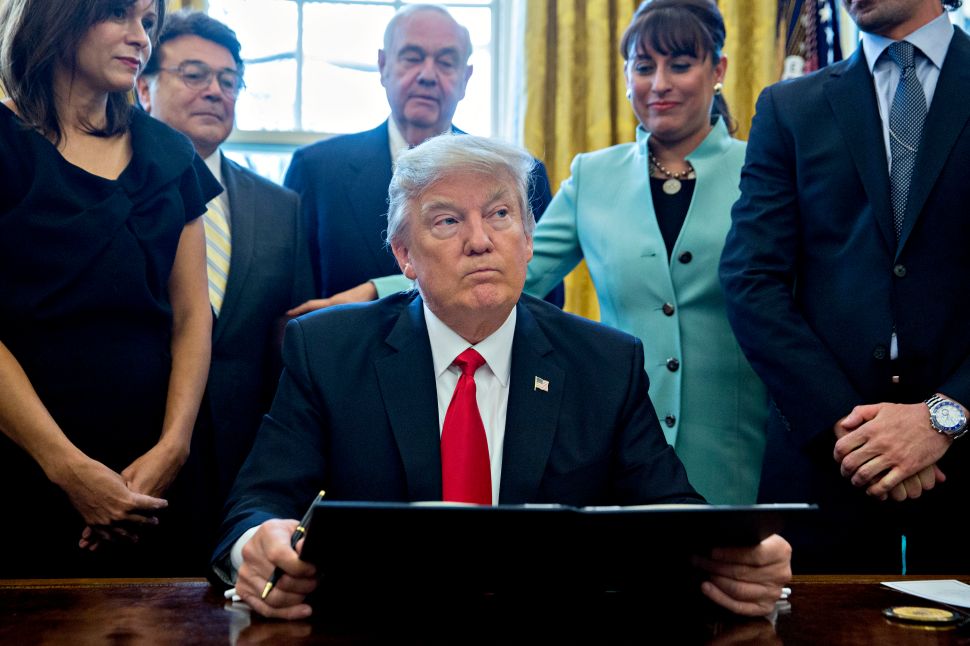 President Donald Trump signs an executive order in the Oval Office of the White House on January 30, 2017 in Washington, DC.