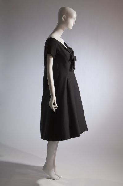 Black wool trapeze line dress; wide modified sweetheart neck with self bow; short kimono sleeves; below-knee length with soft flare; loosely shaped back; Dior; trapeze; The Museum at FIT