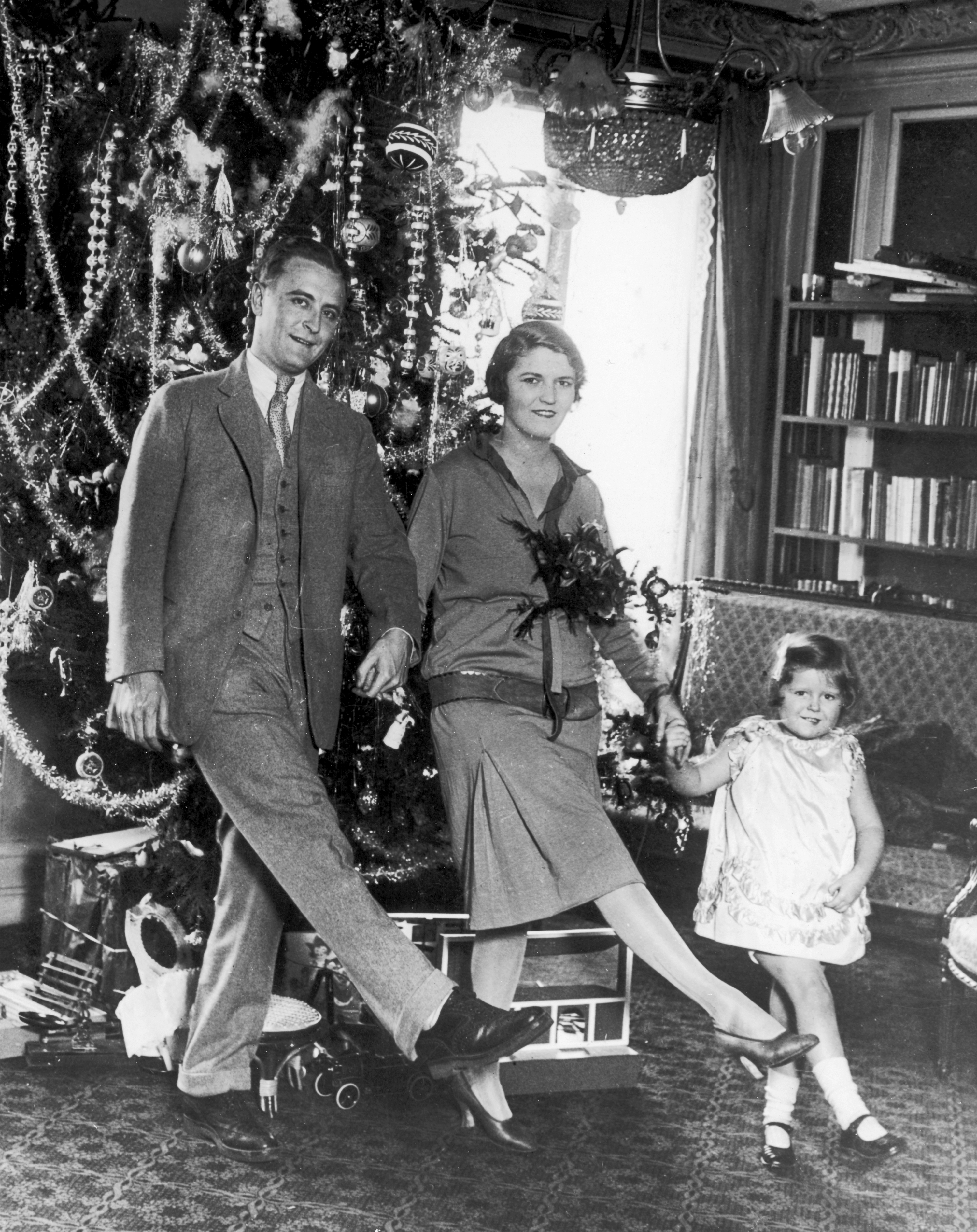 American author F Scott Fitzgerald (1896 - 1940) dances with his wife Zelda Fitzgerald (nee Sayre) (1900 - 1948) and daughter Frances (aka 'Scottie') in front of the Christmas tree in Paris. (Photo by Hulton Archive/Getty Images)