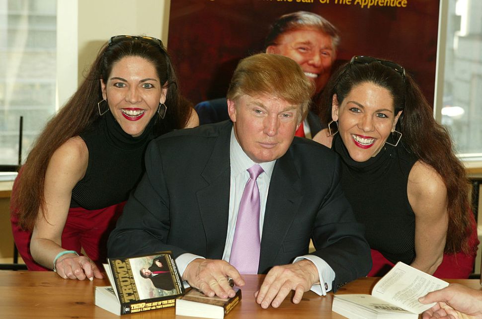 NEW YORK - MARCH 24: Donald Trump poses for a picture with two fans while he signs copies of his new book "How To Get Rich" March 24, 2004 at Barnes and Noble in Lincoln Center in New York City. (Photo by Peter Kramer/Getty Images)