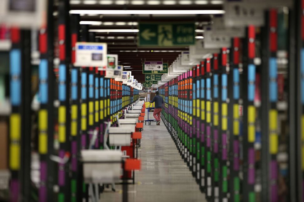 HEMEL HEMPSTEAD, ENGLAND - DECEMBER 05: A worker retrieves goods from shelves at Amazon's warehouse on December 5, 2014 in Hemel Hempstead, England. In the lead up to Christmas, Amazon is experiencing the busiest time of the year. (Photo by Peter Macdiarmid/Getty Images)