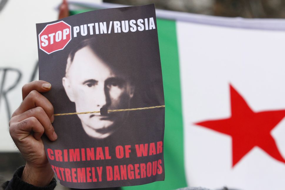 BERLIN, GERMANY - DECEMBER 07: A protester holds a placard showing a portrait of Russian President Vladimir Putin altered to look like Adolph Hitler during a demostration to demand an end to Russian aerial bombing of the Syrian city of Aleppo in front of the Russian Embassy on December 7, 2016 in Berlin, Germany. The Russian military is supporting Syrian government military forces fighting rebels in Aleppo with aerials bombardments that, according to independent observers, has resulted in the heavy loss of civilian lives. 