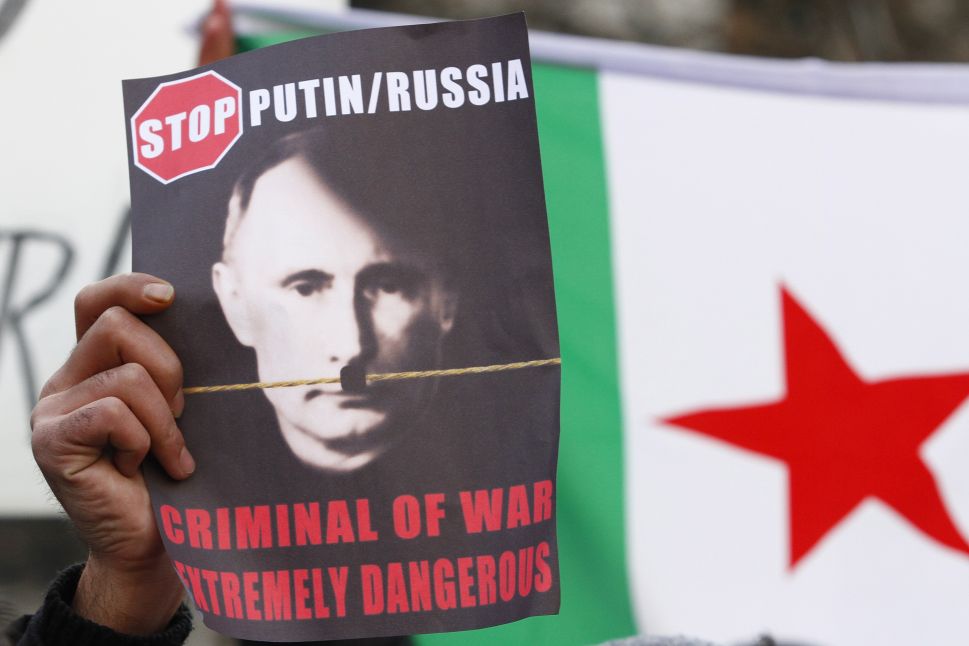 BERLIN, GERMANY - DECEMBER 07: A protester holds a placard showing a portrait of Russian President Vladimir Putin altered to look like Adolph Hitler during a demostration to demand an end to Russian aerial bombing of the Syrian city of Aleppo in front of the Russian Embassy on December 7, 2016 in Berlin, Germany. The Russian military is supporting Syrian government military forces fighting rebels in Aleppo with aerials bombardments that, according to independent observers, has resulted in the heavy loss of civilian lives.