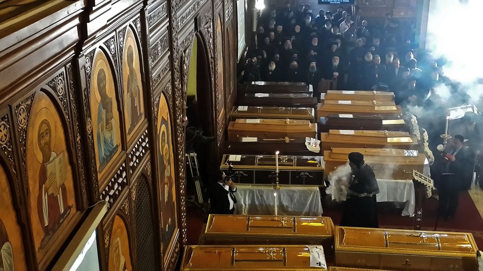 Egyptian clergymen stand next to the coffins of the victims.