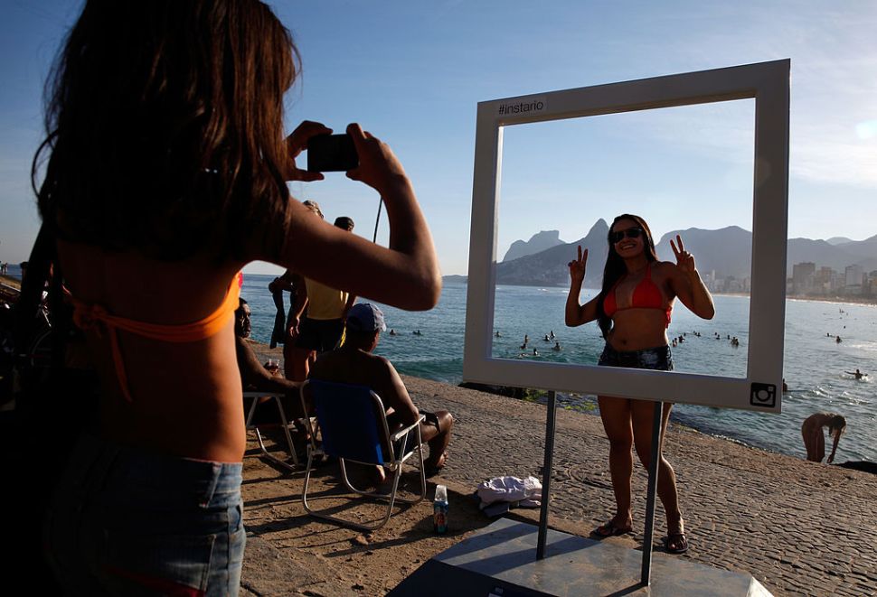 RIO DE JANEIRO, BRAZIL - JUNE 08: A beachgoer poses for a photo at a suggested Instagram spot on Ipanema Beach as the 2014 FIFA World Cup nears on June 8, 2014 in Rio de Janeiro, Brazil. (Photo by Jamie Squire/Getty Images)