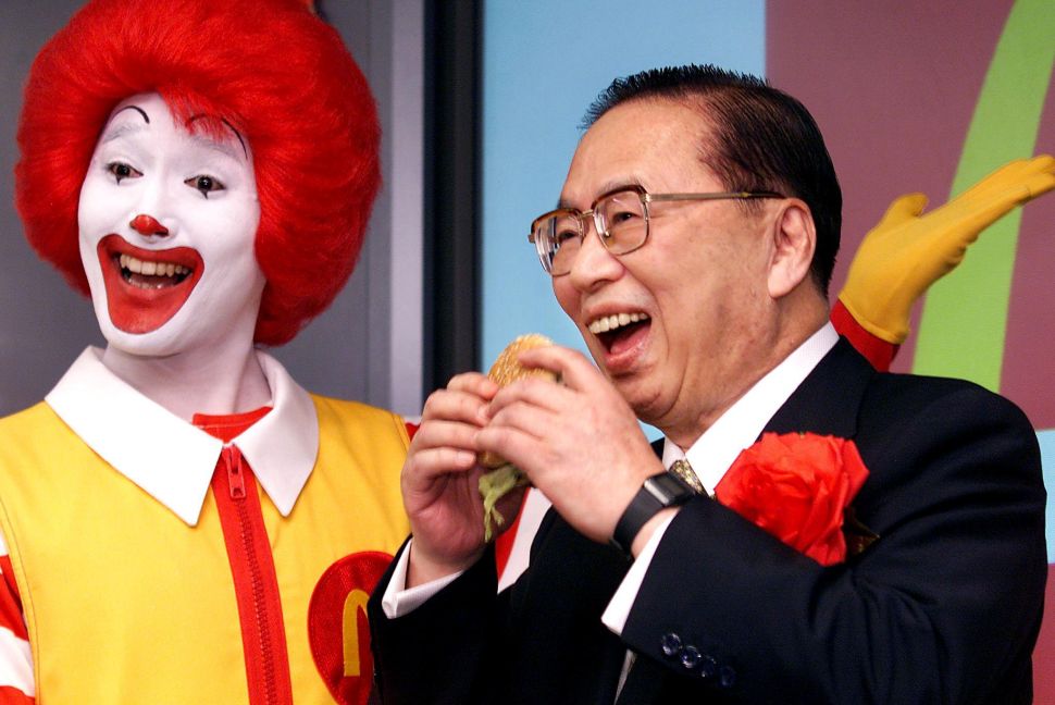TOKYO, JAPAN: Fast food giant McDonald's (Japan) president, Den Fujita (R) bites into a BigMac as the company's stock is listed on the Jasdaq over-the-counter market in Tokyo, 26 July 2001, while McDonald's mascot Ronald (L) smiles. McDonald's shares were fixed at 4,700 yen (39.10 USD) on the first day of trading, compared to the initial public offer price of 4,300 yen (35.80 USD). AFP PHOTO/Yoshikazu TSUNO (Photo credit should read YOSHIKAZU TSUNO/AFP/Getty Images)