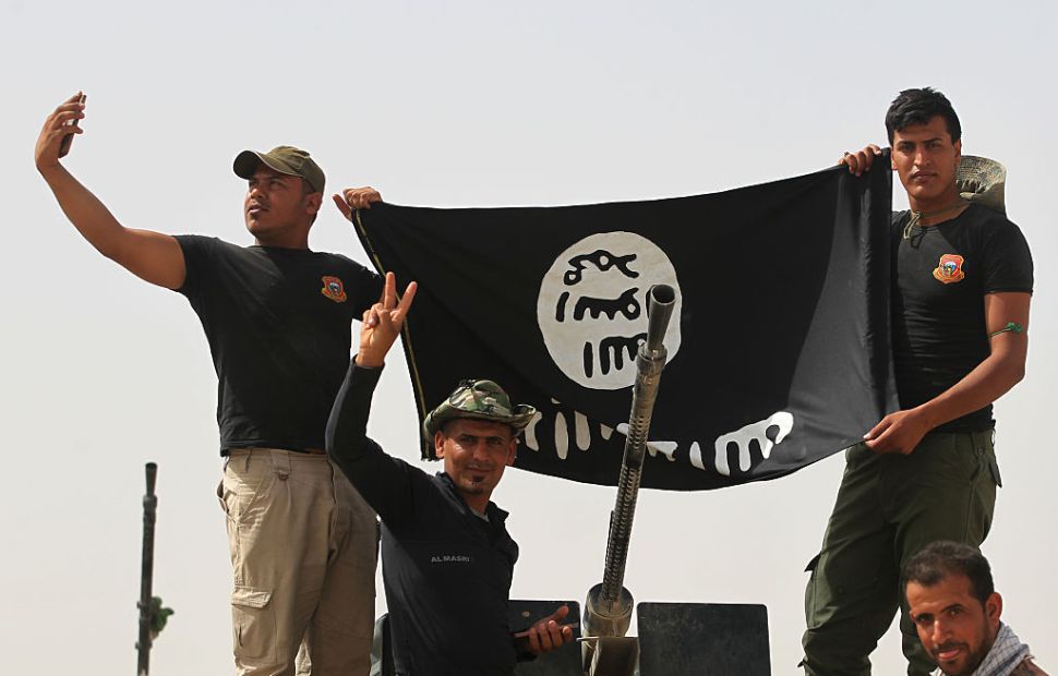 Shiite fighters from the Popular Mobilisation units hold an Islamic State (IS) group upside down in the village of al-Azraqiyah as they advance towards the centre of Saqlawiyah, north west of Fallujah, on June 4, 2016, during an operation to regain territory from the jihadist group. Iraqi pro-government forces, made up of fighters from the army, the police and from the Hashed al-Shaabi, gained new ground from the Islamic State group in a key area west of the jihadist bastion of Fallujah, security sources said.