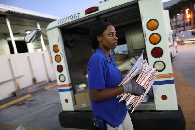 MIAMI, FL - DECEMBER 19: Debbie Kudehinbu, a U.S. Postal Service mail handler, unloads a mail truck at a Processing and Distribution Center on the busiest mailing day of the year for the U.S. Postal Service on December 19, 2016 in Miami, Florida. With 6 days to go until Christmas, today the postal service was expecting a crush of mail to be sent, from first class letters to priority packages. (Photo by Joe Raedle/Getty Images)