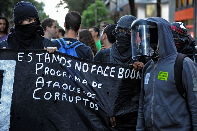 Demonstrators take part in a protest against a public transport fare hike announced for January 2014 by Rio de Janeiro's Mayor Eduardo Paes, in the streets of the Brazilian city, on December 20, 2013. The banner reads "We Are in Facebook: Programme of Attacks Against the Corrupt". AFP PHOTO/TASSO MARCELO (Photo credit should read TASSO MARCELO/AFP/Getty Images)
