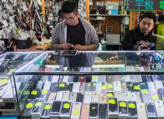 This picture taken on January 13, 2017 shows workers in a secondhand mobile phone store in the Sham Shui Po district of Hong Kong. Electronic waste is rising sharply across Asia as higher incomes allow hundreds of millions of people to buy smartphones and other gadgets, with serious consequences for human health and the environment, according to a UN study released on January 15. / AFP / Isaac LAWRENCE (Photo credit should read ISAAC LAWRENCE/AFP/Getty Images)