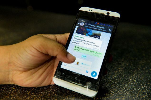 A person holds a mobile phone showing a Whatsapp group chat for the exchange of scarce products in Caracas on June 13, 2016. / AFP / FEDERICO PARRA / TO GO WITH AFP STORY BY MARIA ISABEL SANCHEZ (Photo credit should read FEDERICO PARRA/AFP/Getty Images)