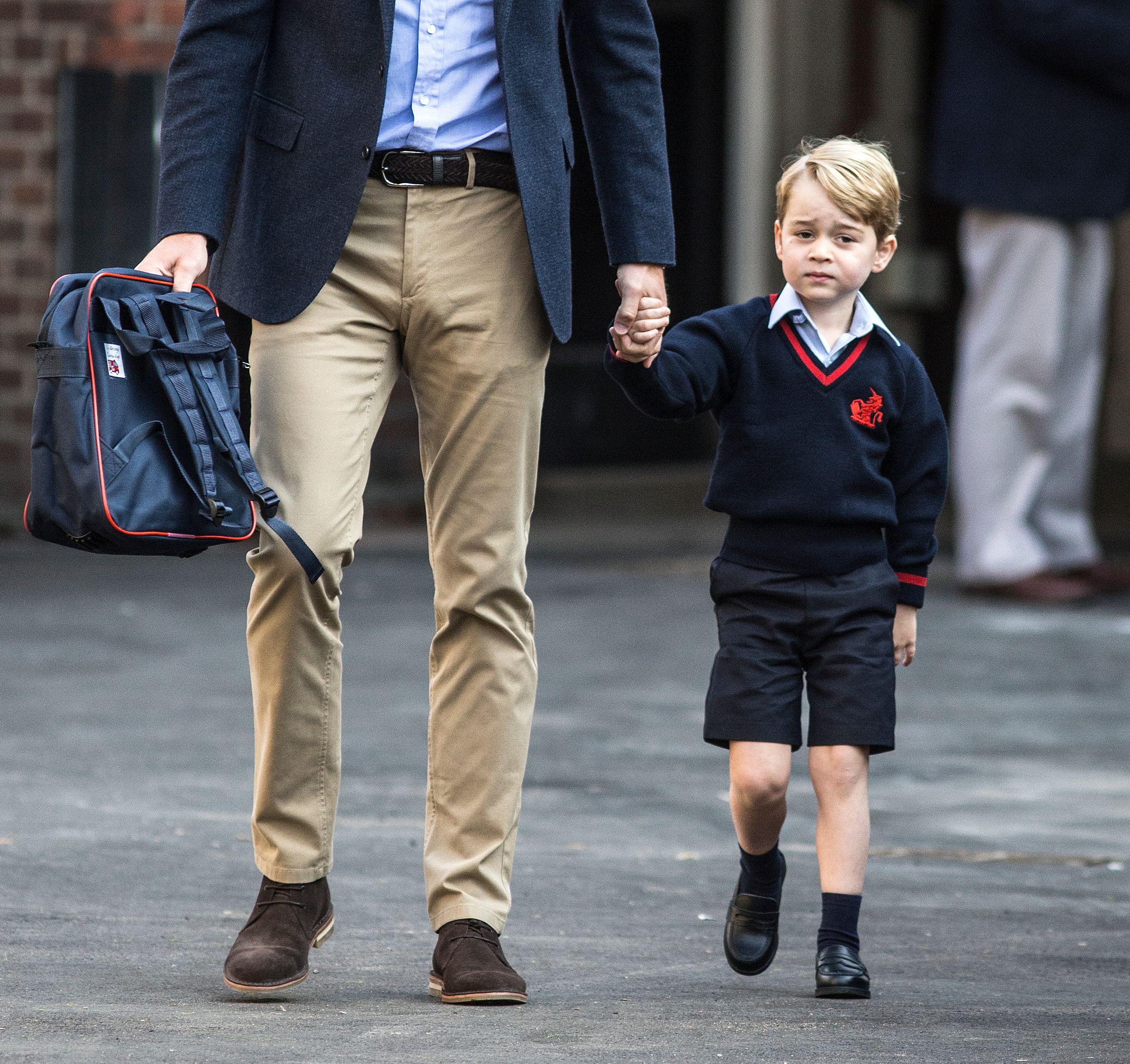 Britain's Prince George accompanied by Britain's Prince William, Duke of Cambridge arrives for his first day of school at Thomas's school on September 7, 2017 in southwest London. /