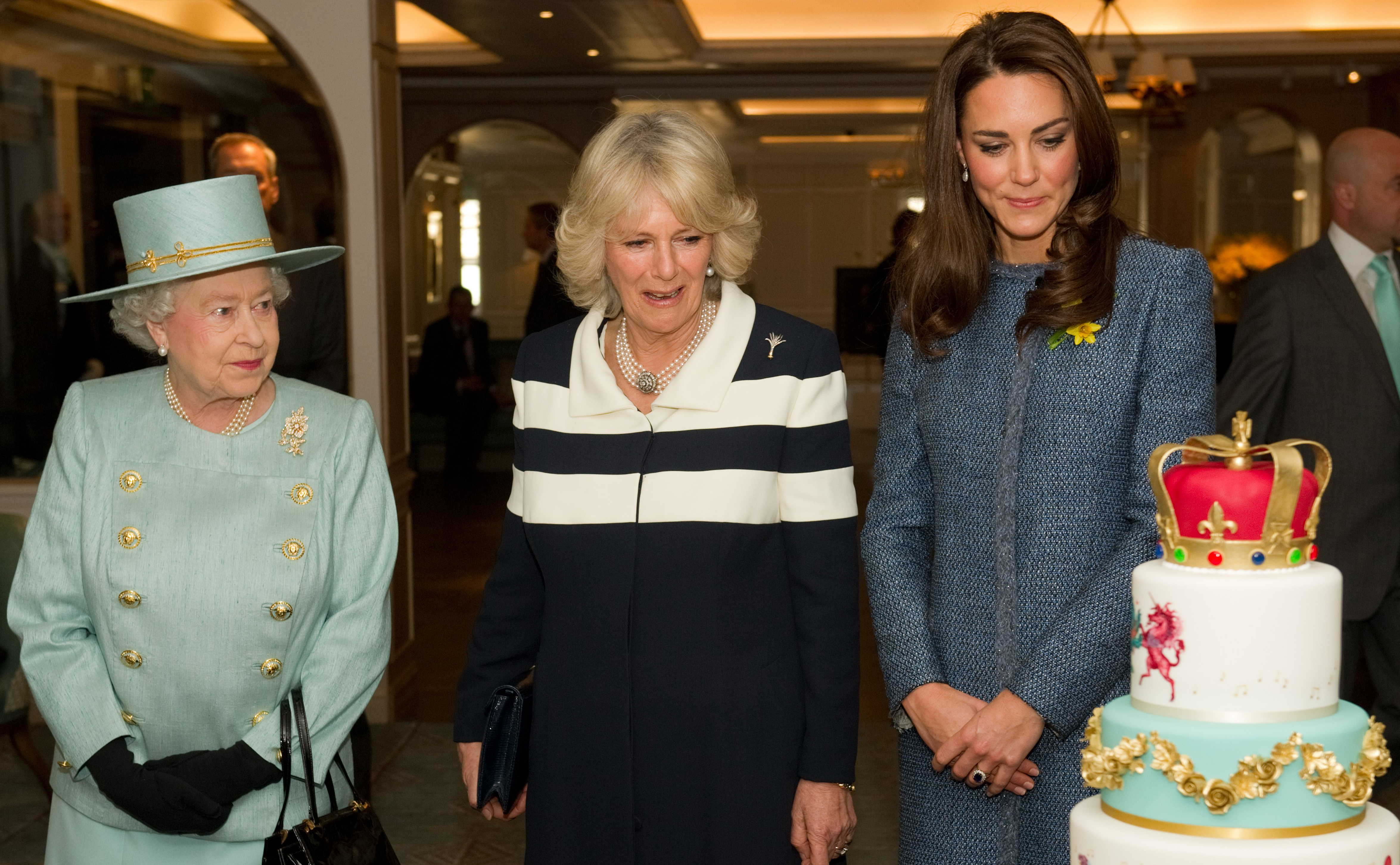Britain's Queen Elizabeth II (L), Catherine, Duchess of Cambridge (R), and Camilla, Duchess of Cornwall (C), look at a jubilee cake during an offical vist to a department store in central London on March 1, 2012. The queen unveiled a plaque on the pavement to commemorate the refurbishment of Piccadily upon departure after touring the Fortnum and Mason store with their royal highnesses. AFP PHOTO / POOL / LEON NEAL (Photo credit should read LEON NEAL/AFP/Getty Images)