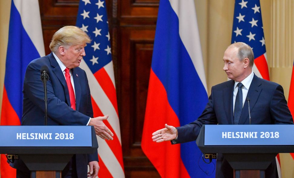 U.S. President Donald Trump (L) and Russia's President Vladimir Putin reach out to shake hands before attending a joint press conference after a meeting at the Presidential Palace in Helsinki, on July 16, 2018. 