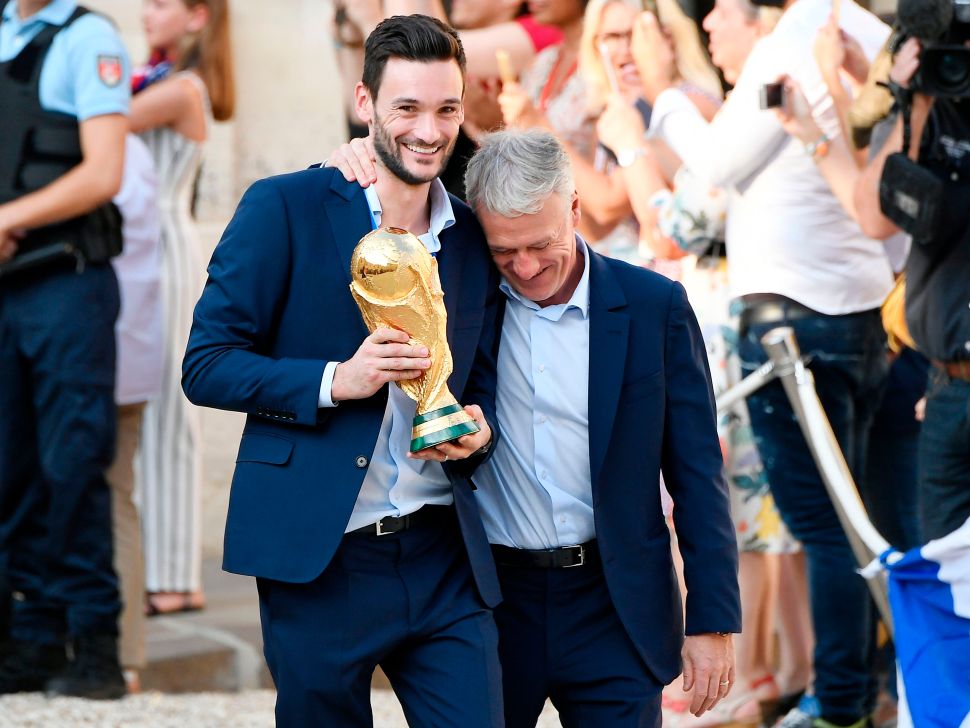 TOPSHOT - France's goalkeeper Hugo Lloris (L) smiles and holds the trophy next to France's coach Didier Deschamps as they arrive for a reception at the Elysee Presidential Palace on July 16, 2018 in Paris after French players won the Russia 2018 World Cup final football match. - France celebrated their second World Cup win 20 years after their maiden triumph on July 15, 2018, overcoming a passionate Croatia side 4-2 in one of the most gripping finals in recent history.