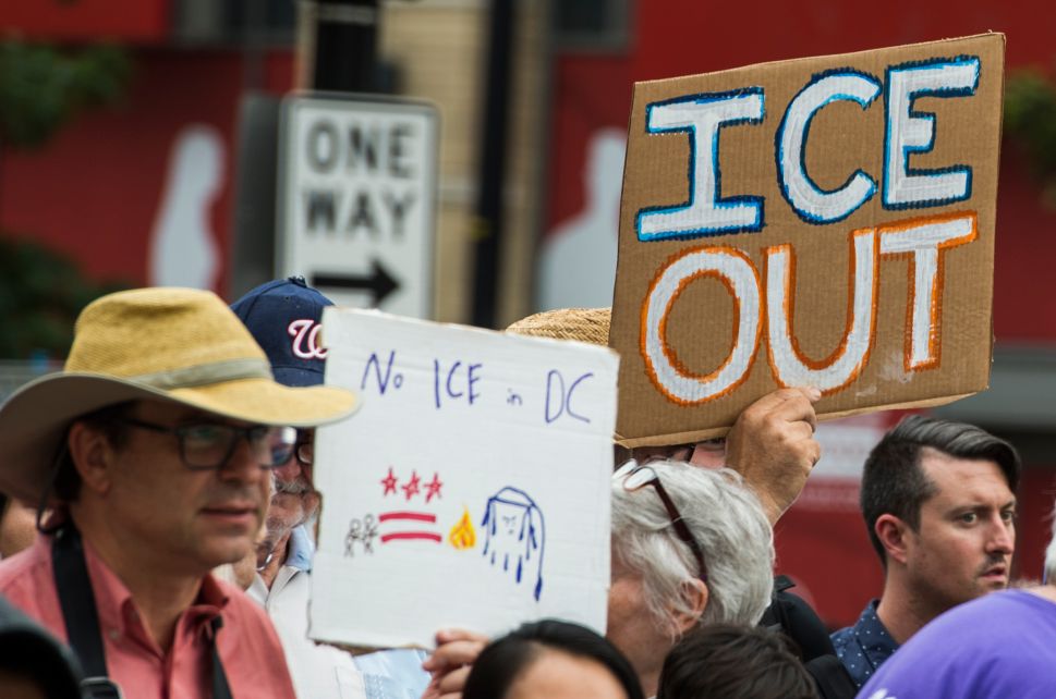 People hold up signs as they protest the U.S. Immigration and Customs Enforcement agency (ICE) and the recent detentions of illegal immigrants.
