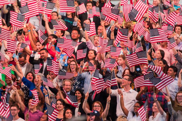 People wave American flags at a primary night rally for Democratic presidential candidate Hillary Clinton in the Brooklyn Navy Yard, June 7, 2016 in Brooklyn, New York. Clinton will become the first woman in U.S. history to secure the presidential nomination of one of the country's two major political parties.